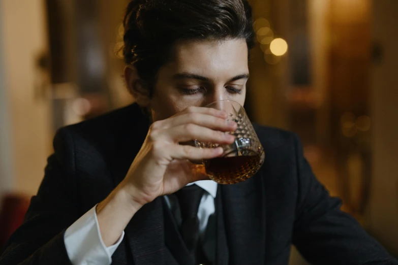 a man in a suit drinks from a glass