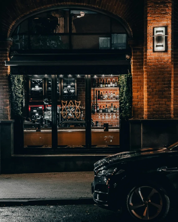 the store has two dark - lit windows, one reflecting a black car