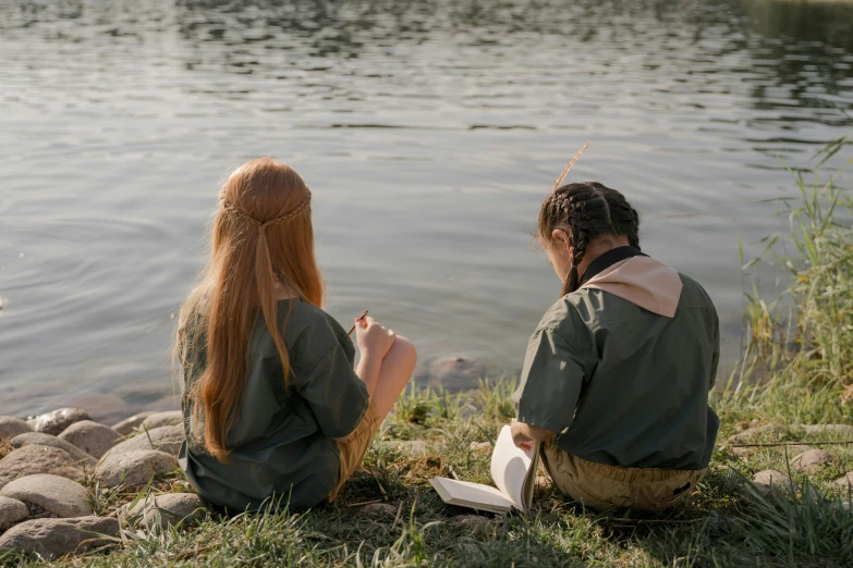 a man and woman sitting next to the water