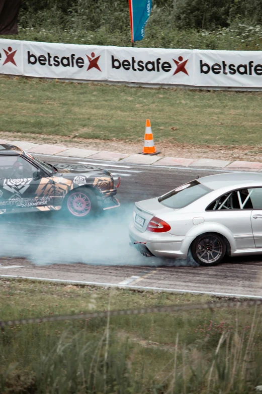 two cars driving side by side in a wet race