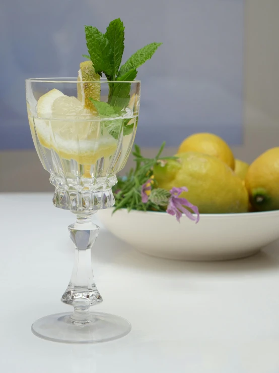 a bowl full of lemons and a glass of water