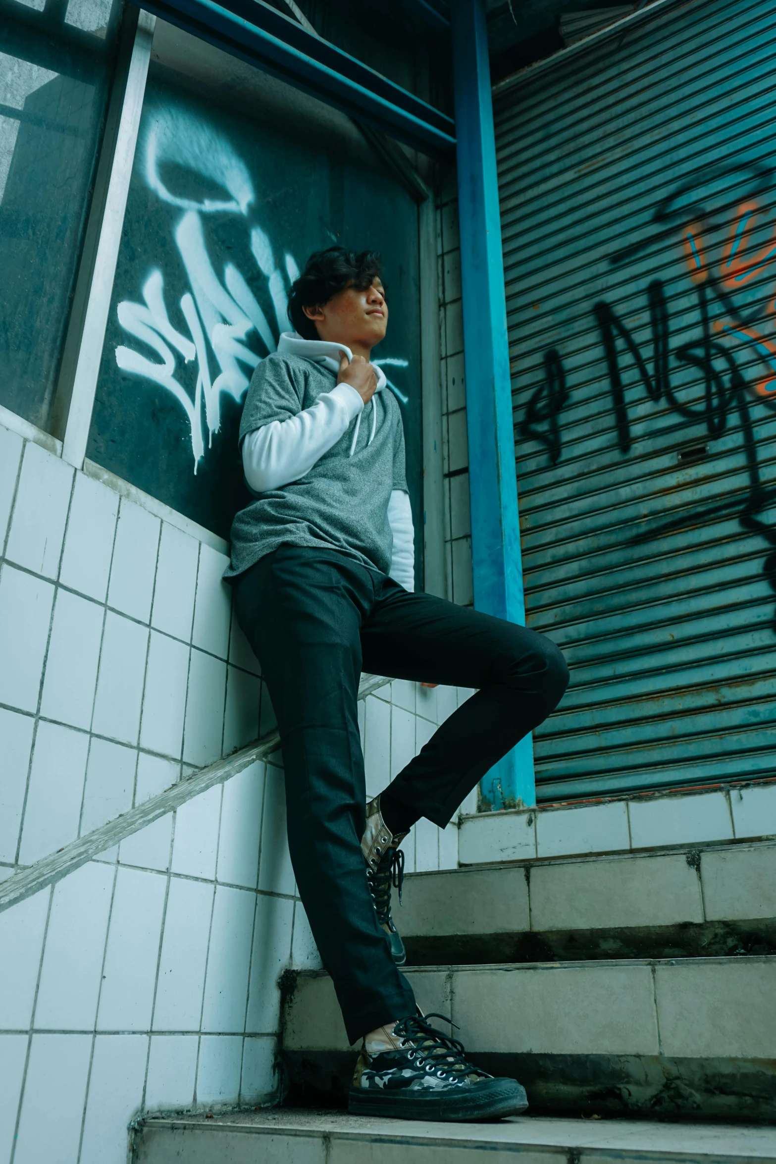 a man is leaning on steps with graffiti on his wall