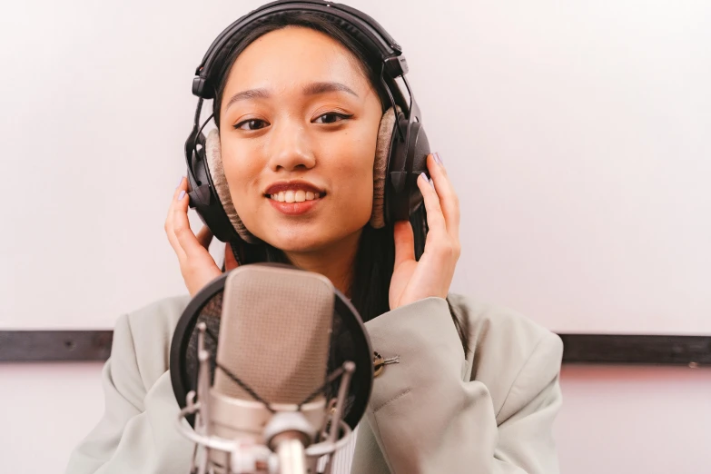 a woman wearing headphones and holding her ears up in front of her microphone