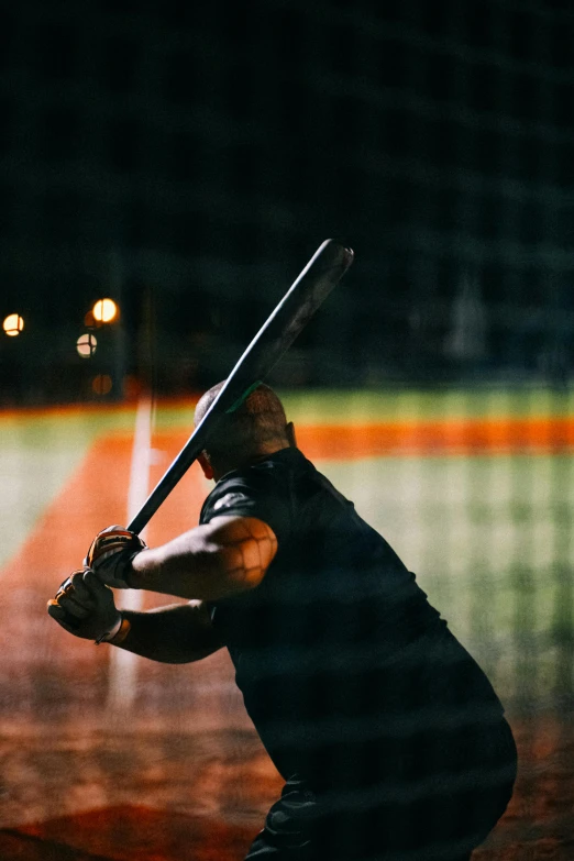 a baseball player is holding his bat in the dark