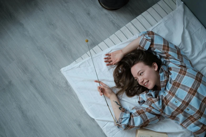 a young woman laying on top of a bed with her hands in the air