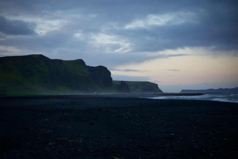 an ocean scene with dark colored rocks in the background