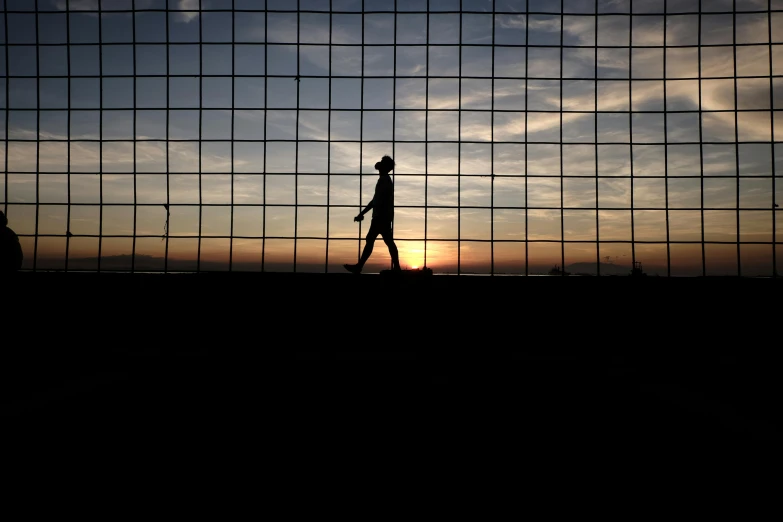 man walking in front of the sunset with a backpack
