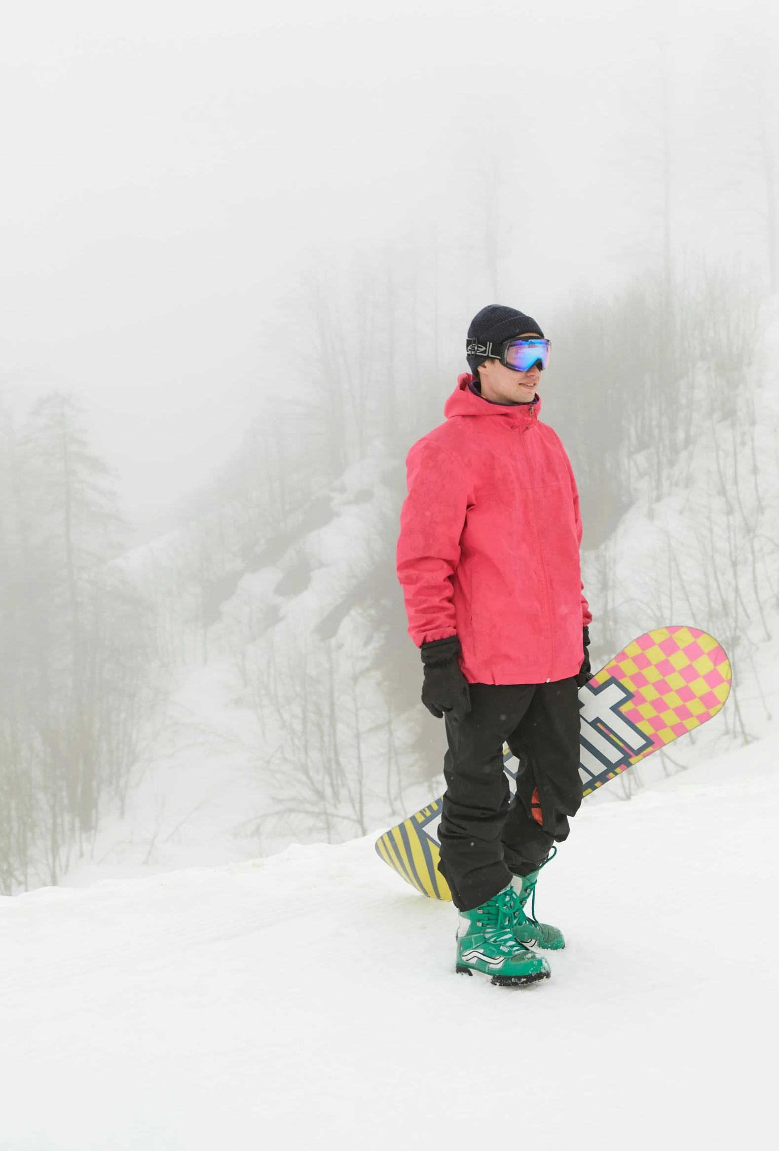 a man wearing a red jacket standing on top of a snow covered ski slope