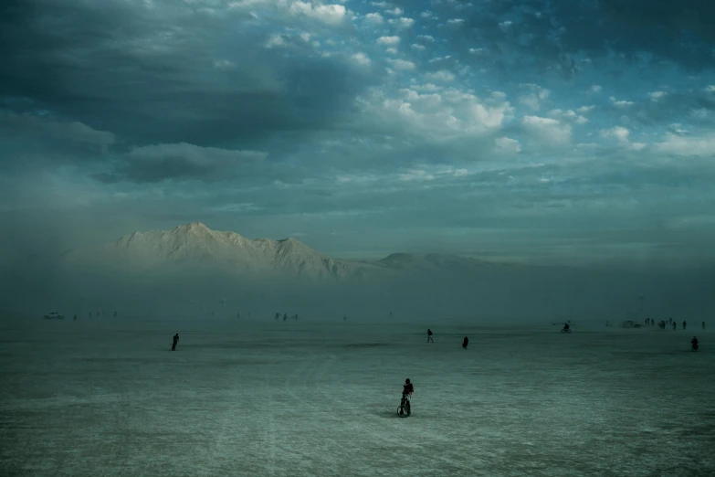 an overcast sky and a group of people out on the beach