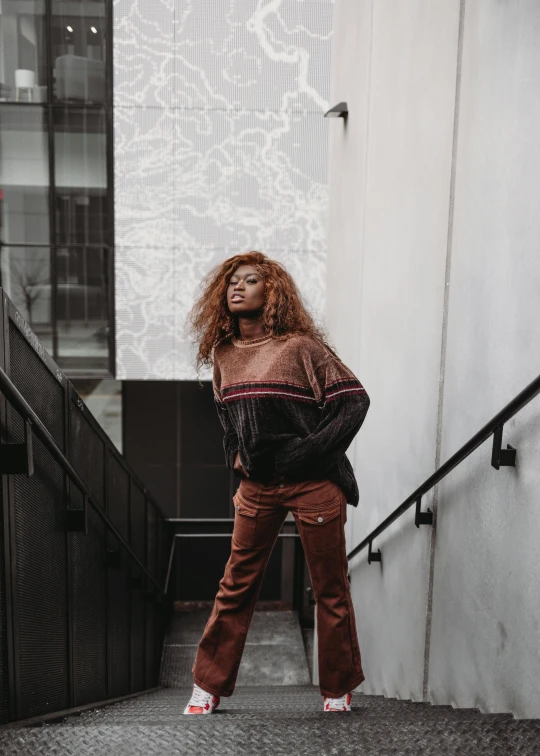 woman with curly hair standing by staircase in front of a white building