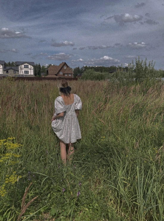 the woman is walking through the tall grass