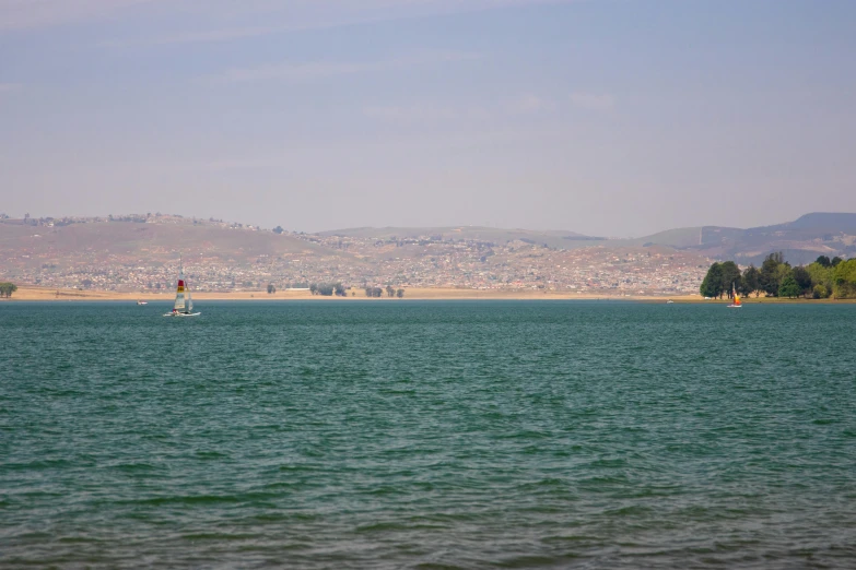 sailboat out on the ocean with city in the background