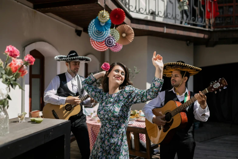 woman with a guitar, three musicians in mexican clothing, playing music outside