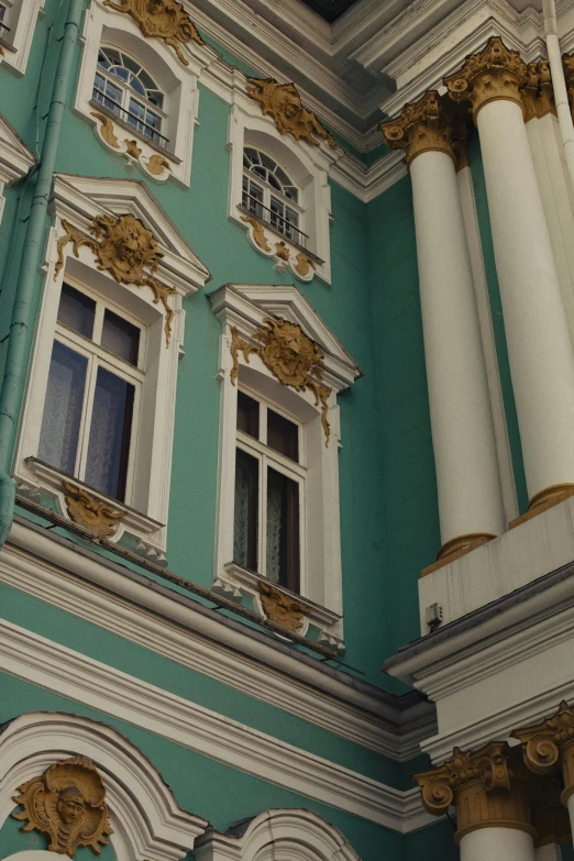 the top part of a green building with white and gold trim