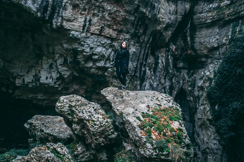 a man standing on top of a large rock near some cliffs