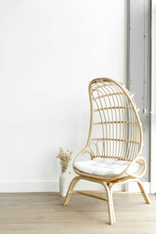 a rattan chair sits on a hard wood floor with white walls