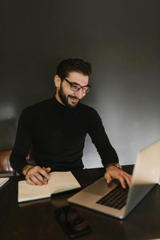 the man is sitting at a table using his laptop