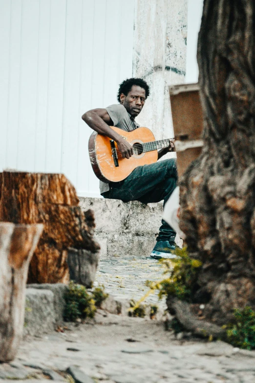 a man sitting down holding a guitar in his lap