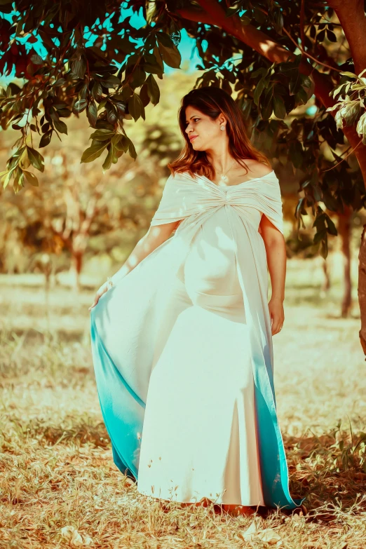 a woman is in an elegant white dress by the tree