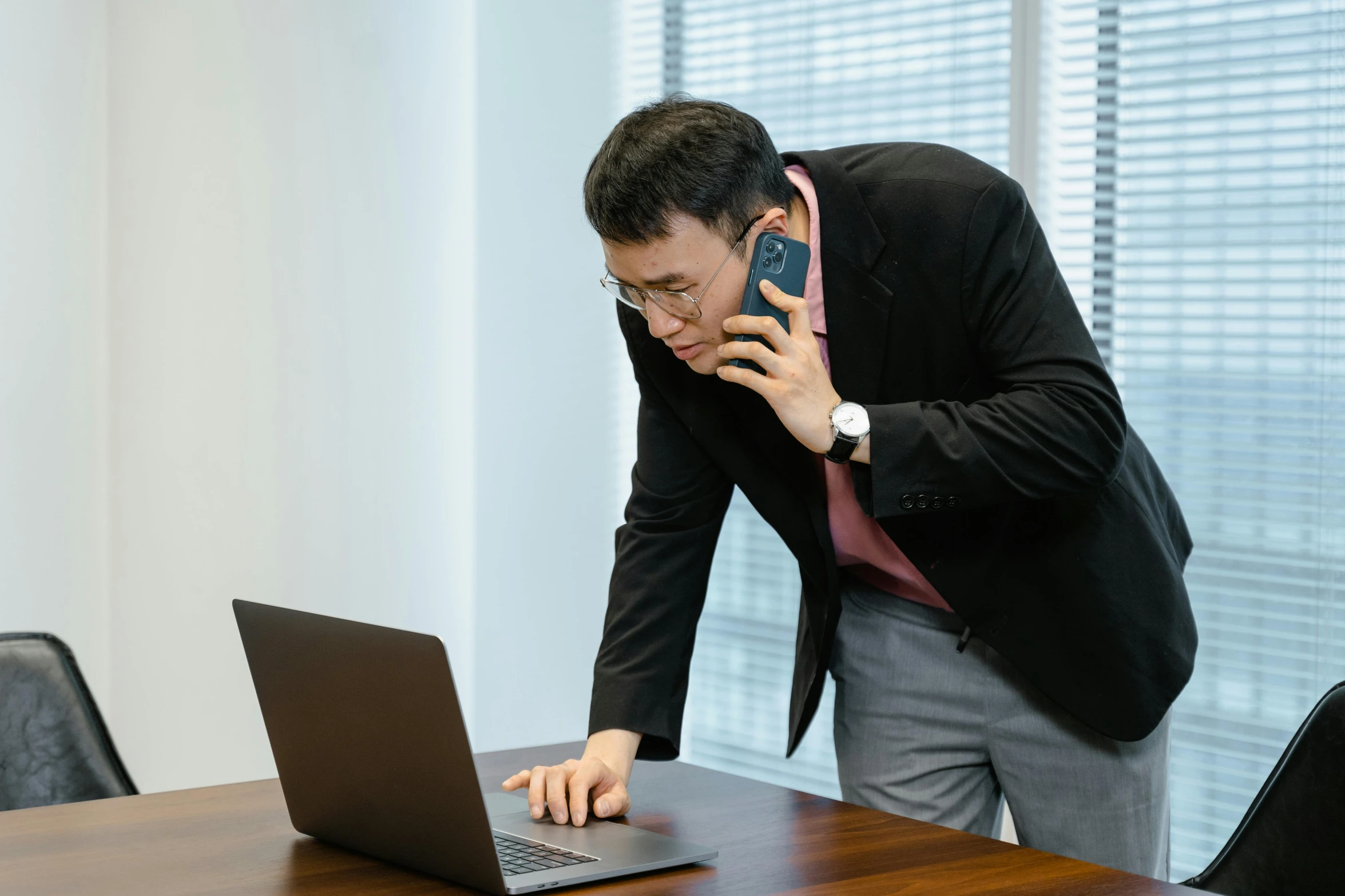 an office worker is looking at his laptop and the phone