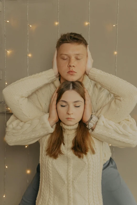 a young man covering his head while holding a woman's head