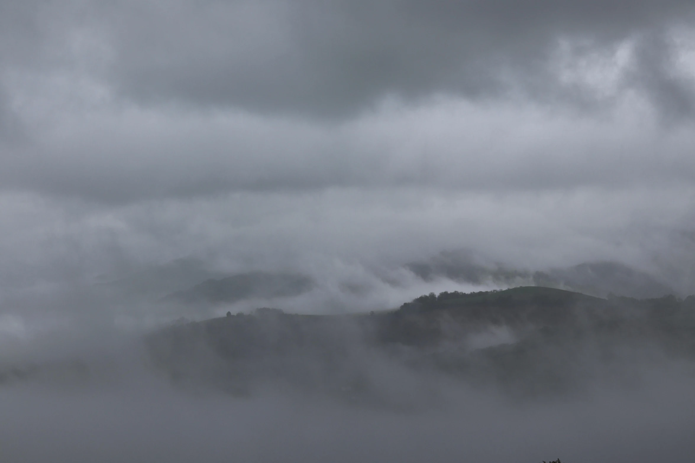 fog, low flying clouds, and a large mountain in the distance