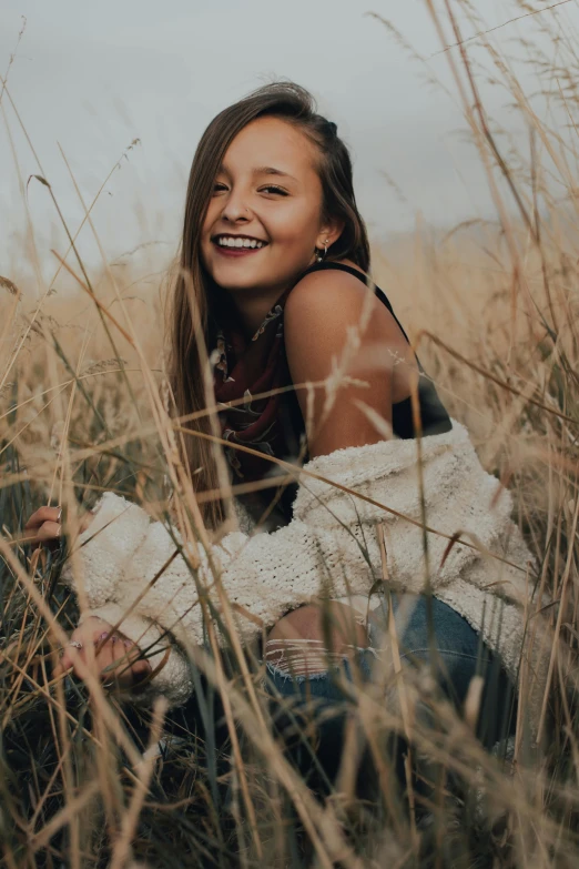 a smiling girl posing for a picture in the tall grass