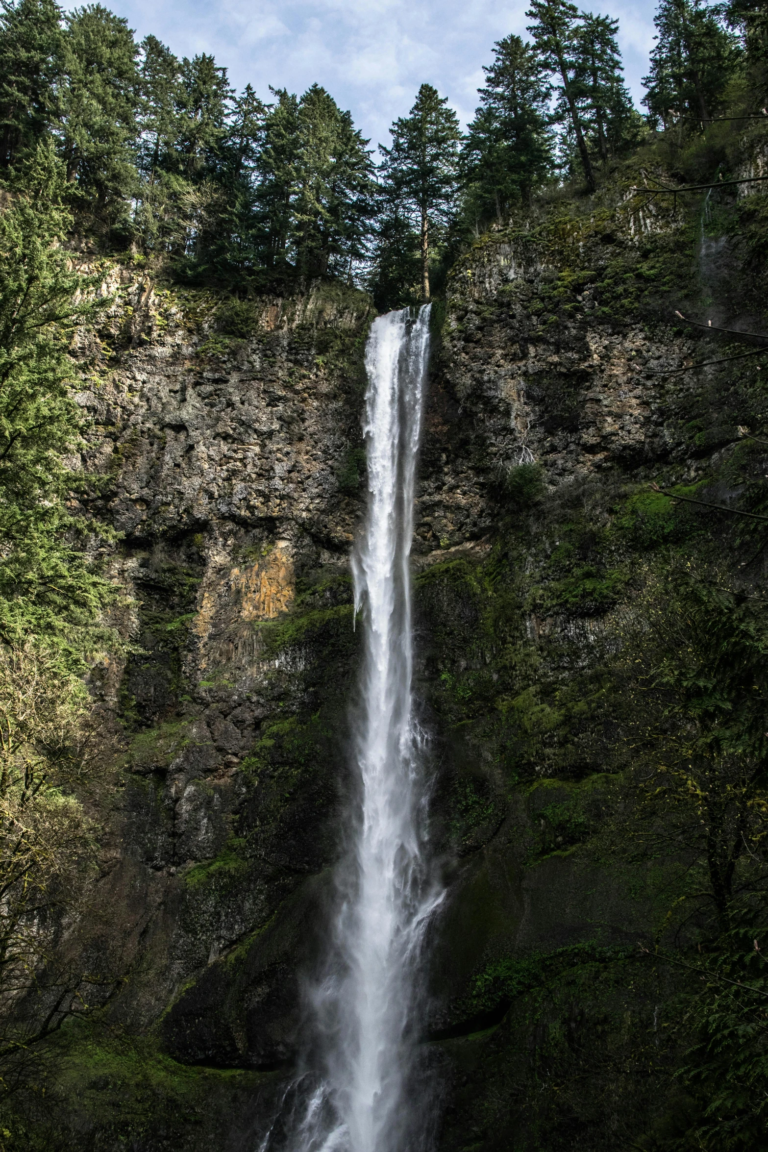 a long waterfall coming out of the side of a mountain