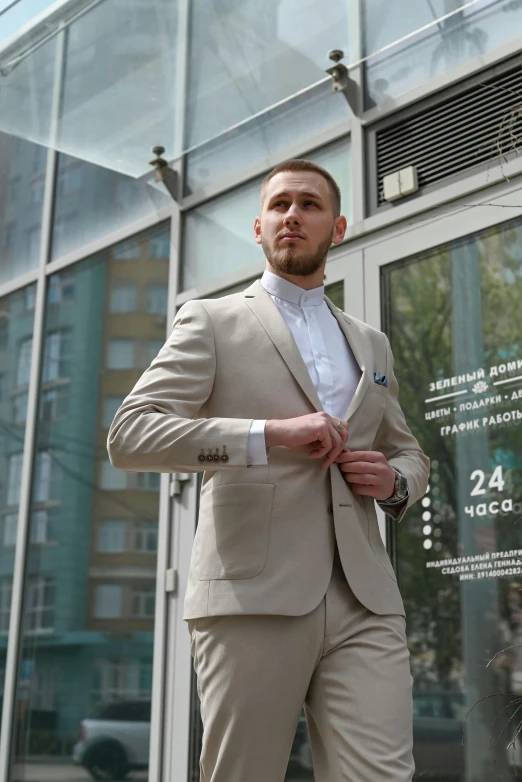 a man in a gray suit standing in front of a building