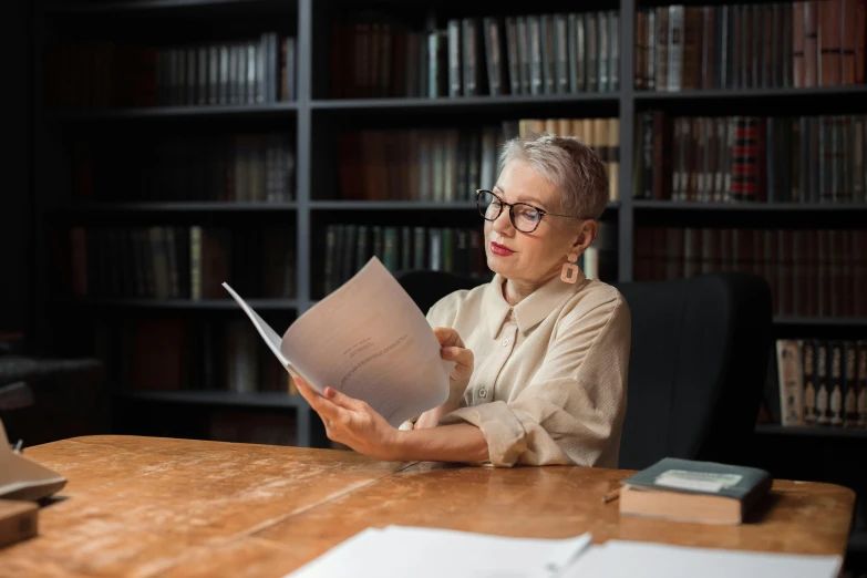 an older woman sitting at a desk and reading books