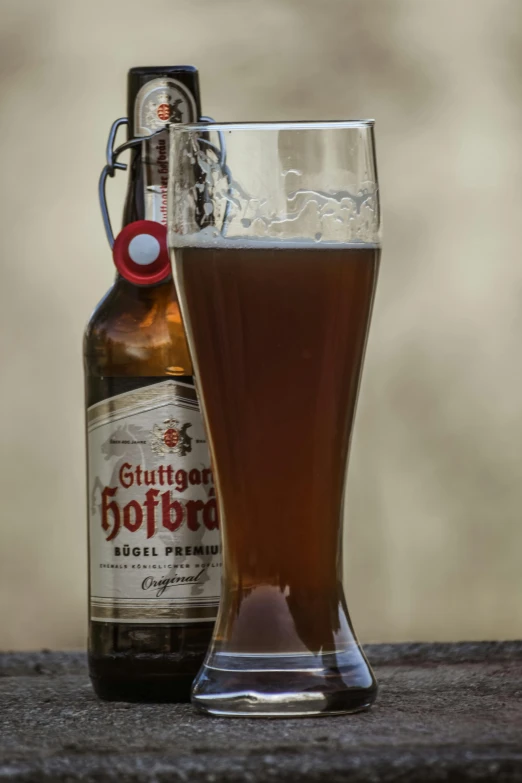 a beer is next to a glass in the shape of a vase