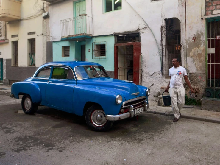 a man walking in the street with his old car