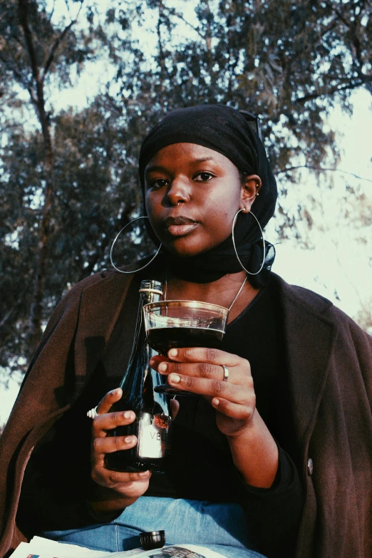 a woman with her hands in her pocket holding a wine bottle