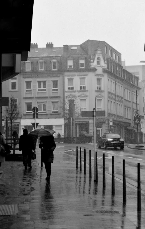 several people walk across a wet street holding umbrellas