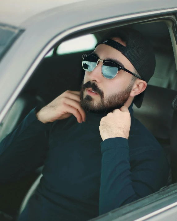 man sitting in a car with glasses on looking out the window