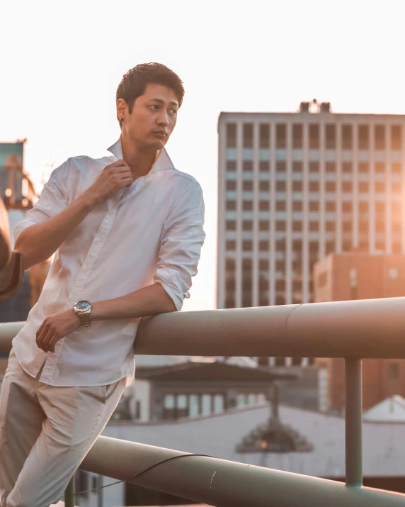 a man wearing white with a watch leaning on the railing