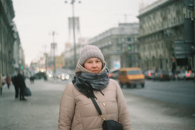 woman in winter jacket standing on street by traffic lights