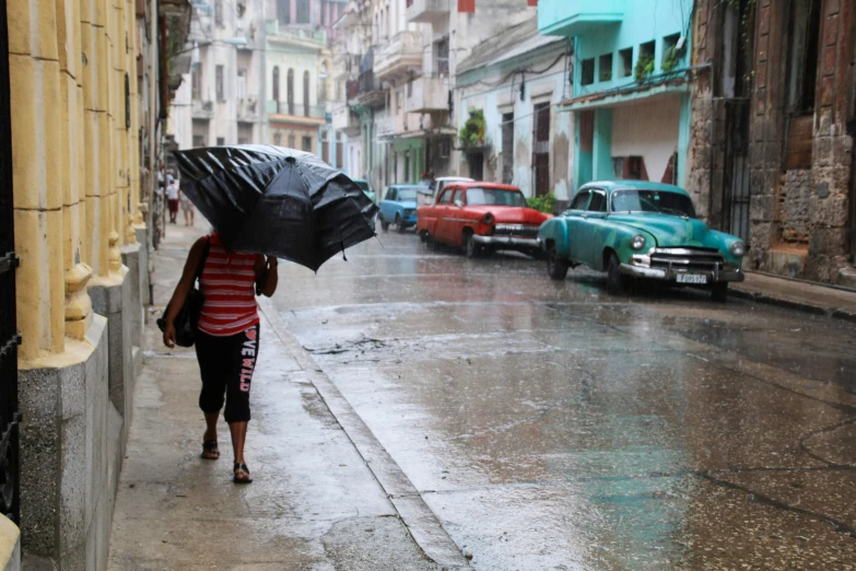 a woman holding an umbrella walks down the street