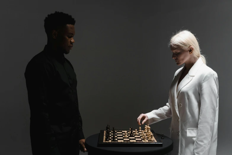 the chess player stands at the back of a chess board as he plays with a person in a white suit