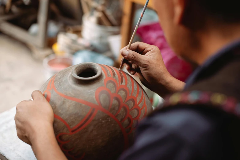 the person is using a brush to make the vase look old