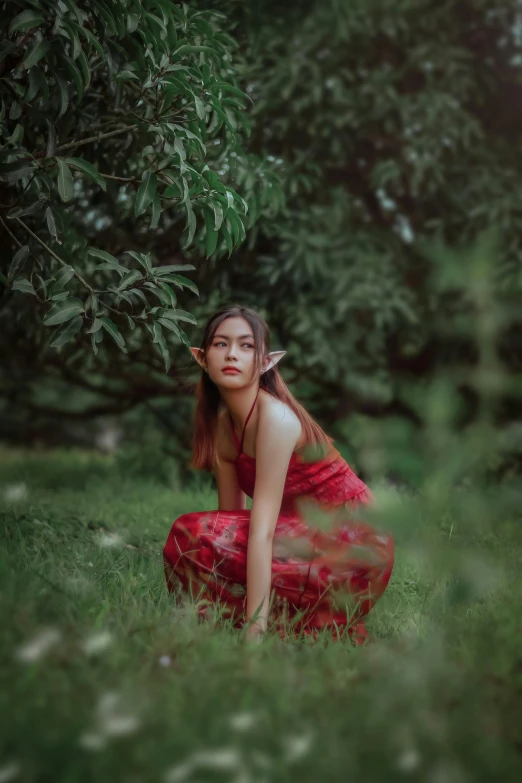 a woman in a red dress sitting next to trees