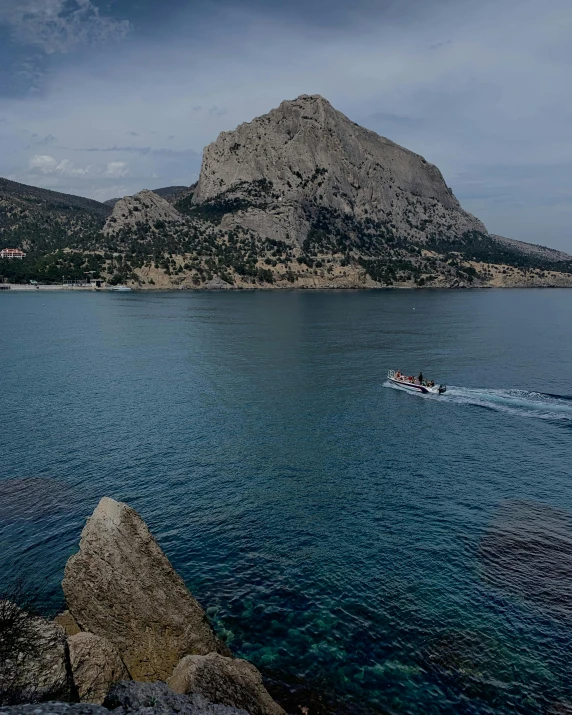 a boat with passengers in the water near a rocky island