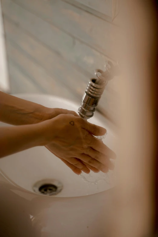 the hand holds the bathroom faucet in front of a sink