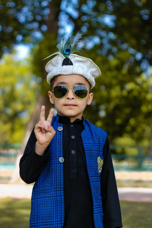 a boy wearing sunglasses and an indian headdress giving the peace sign