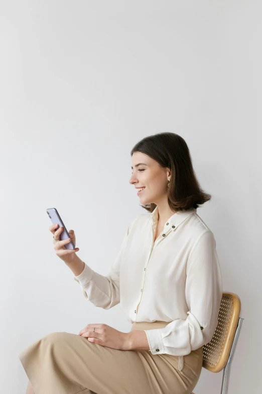 a woman sitting in a chair and looking at her cell phone