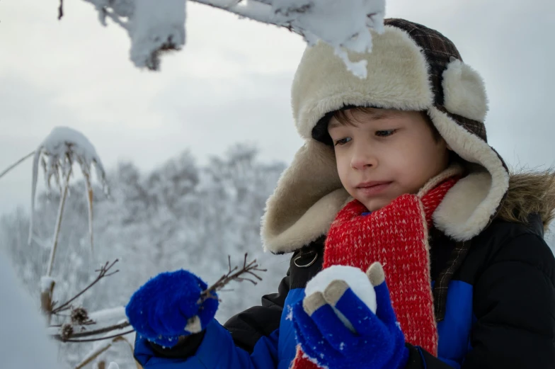 a young child wearing winter clothes holding onto some kind of item
