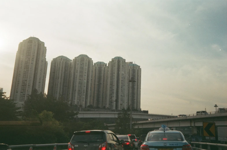 several traffic driving on a road with buildings in the background