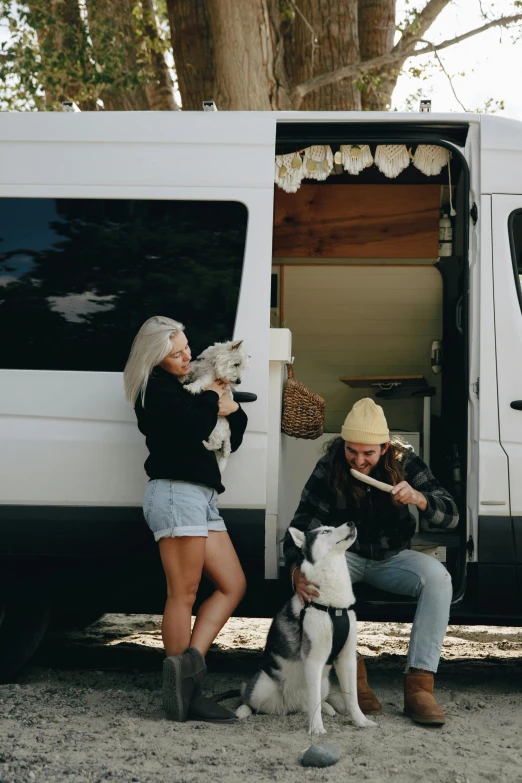 a woman in short shorts and a yellow hat petting a dog