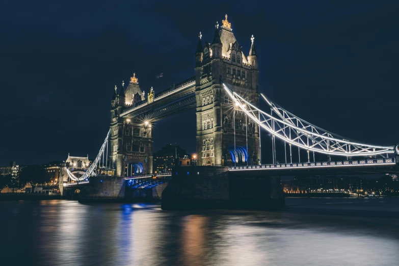 tower bridge at night with city lights across water