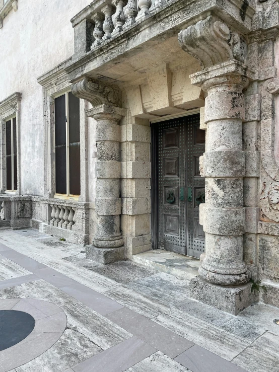 an ornate doorway with black doors between two tall buildings